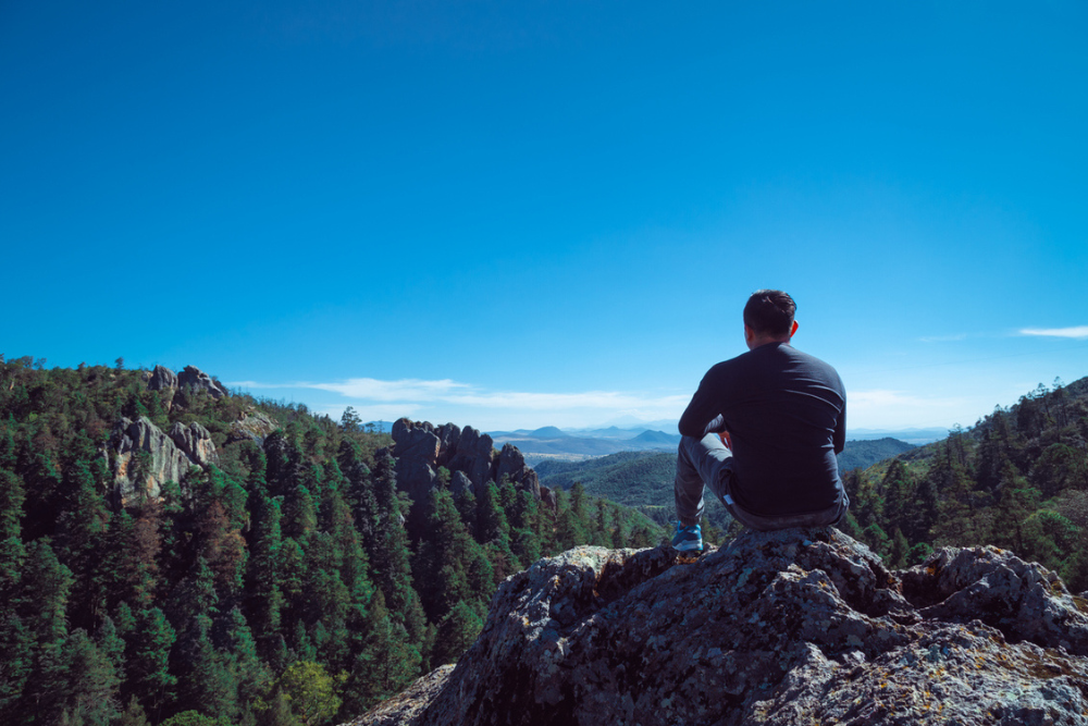 hiker sitting on top of mountain - thrive concept