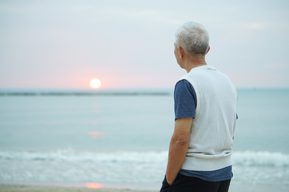 Older man looking at the horizon on the beach